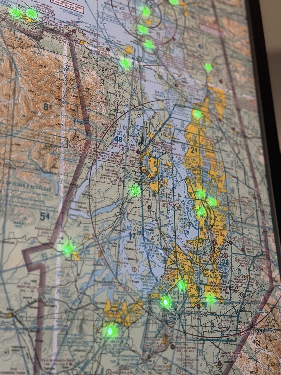 Close-up of a Pacific Northwest sectional chart with green LEDs glowing at airports around Seattle, Tacoma and Puget Sound